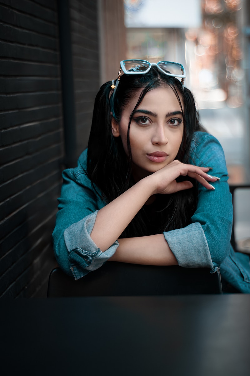 a woman sitting at a table with her hand on her chin